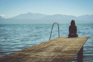woman sitting on a dock at the lake questioning if she has seasonal depression