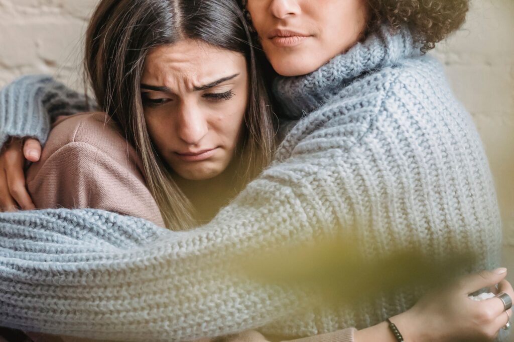Woman struggling with mental health being comforted by woman using somatic therapy techniques
