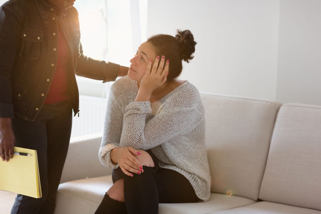 woman who is sitting on the couch with her therapist holdong onto her shoulder during trauma therapy in atlanta