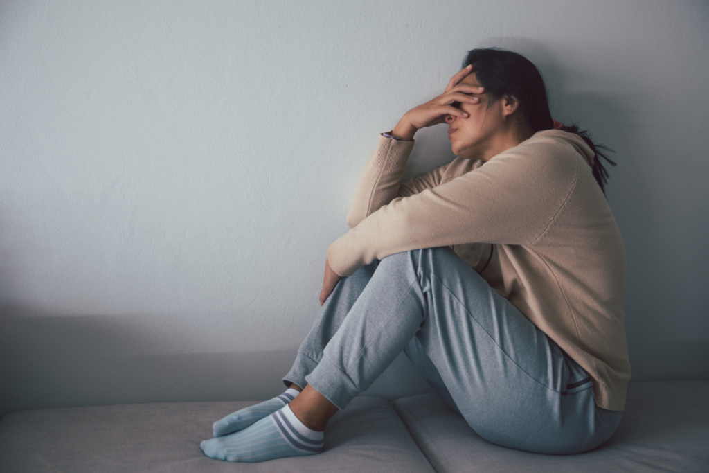 woman sitting on the floor holding her head struggling with Signs her Antidepressant dose is too low