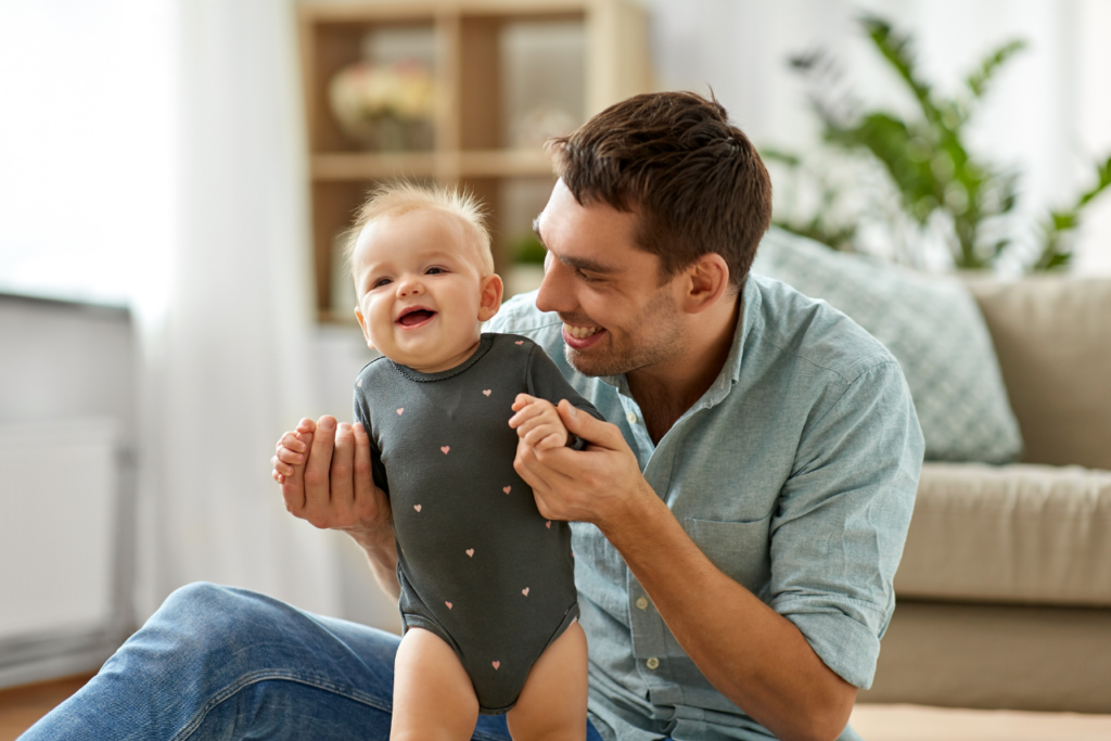 man very happy holding his baby after going to therapy for the question can men get postpartum depression